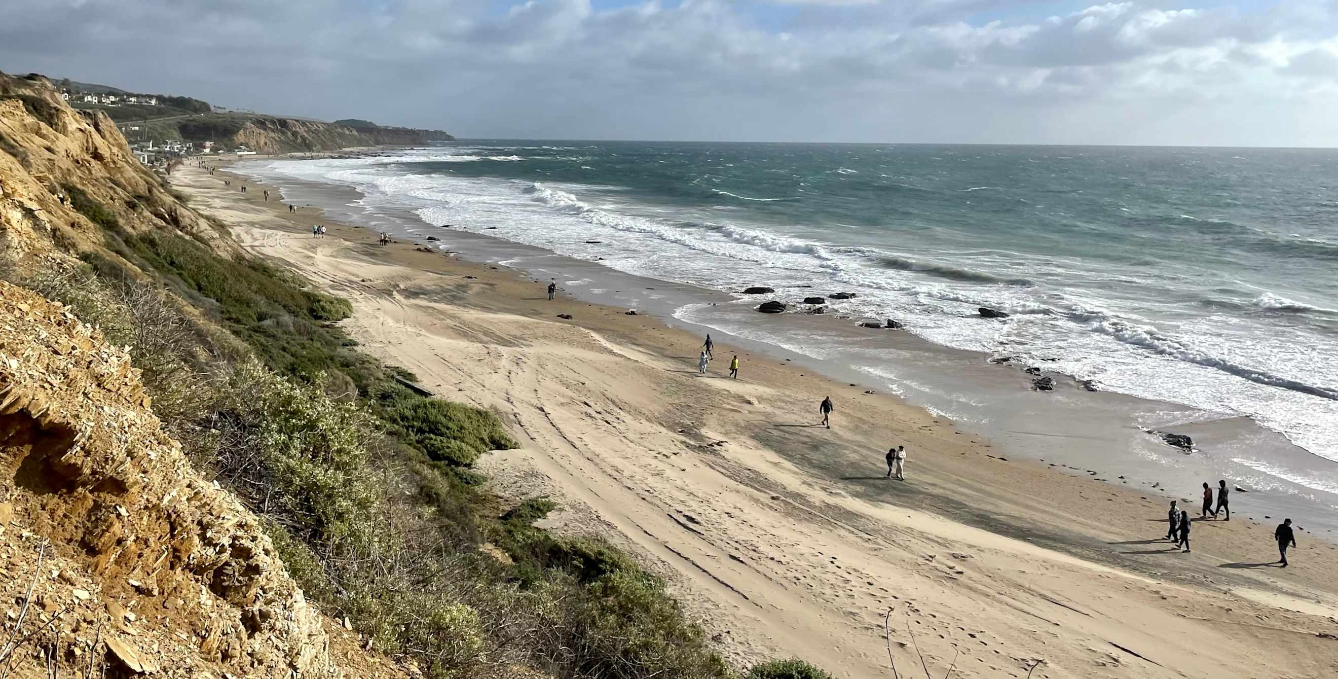 People walk along the breach at Crystal Cove State Park in Newport Beach, California.