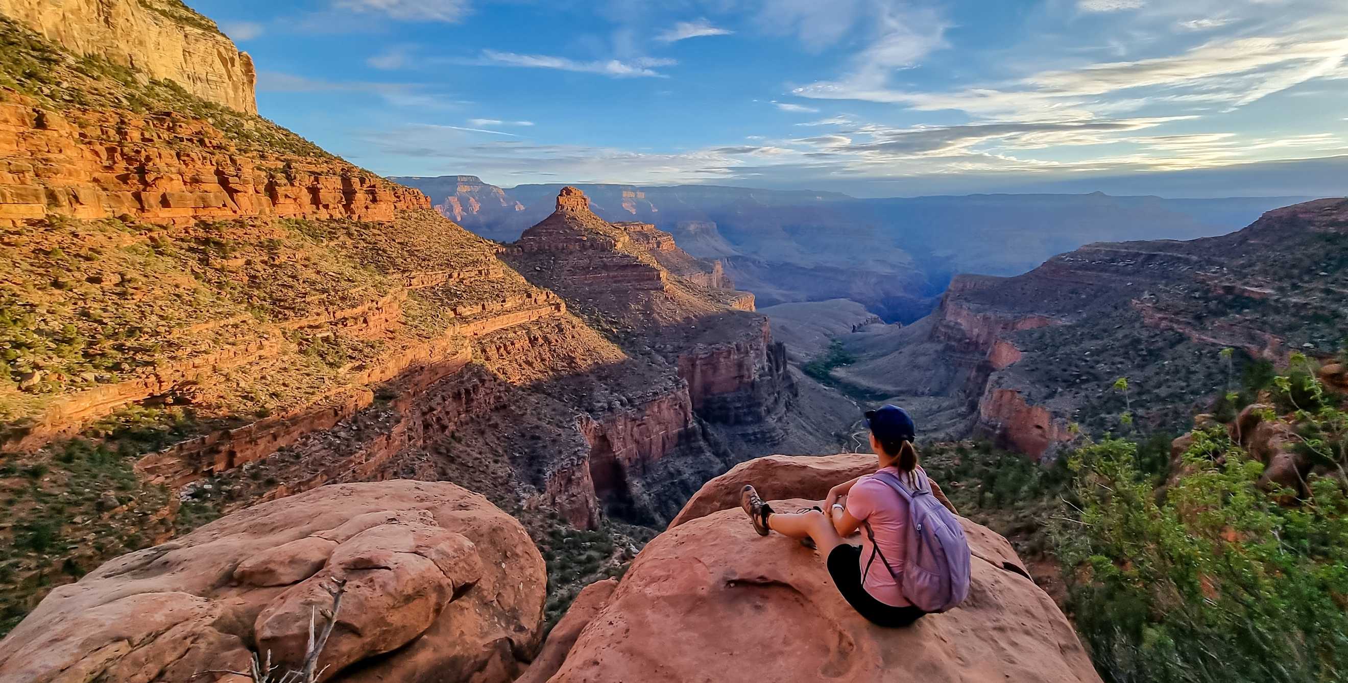 Rear view of woman sitting on rock along Bright Angel trail overlooking South Rim of Grand Canyon National Park, Arizona.