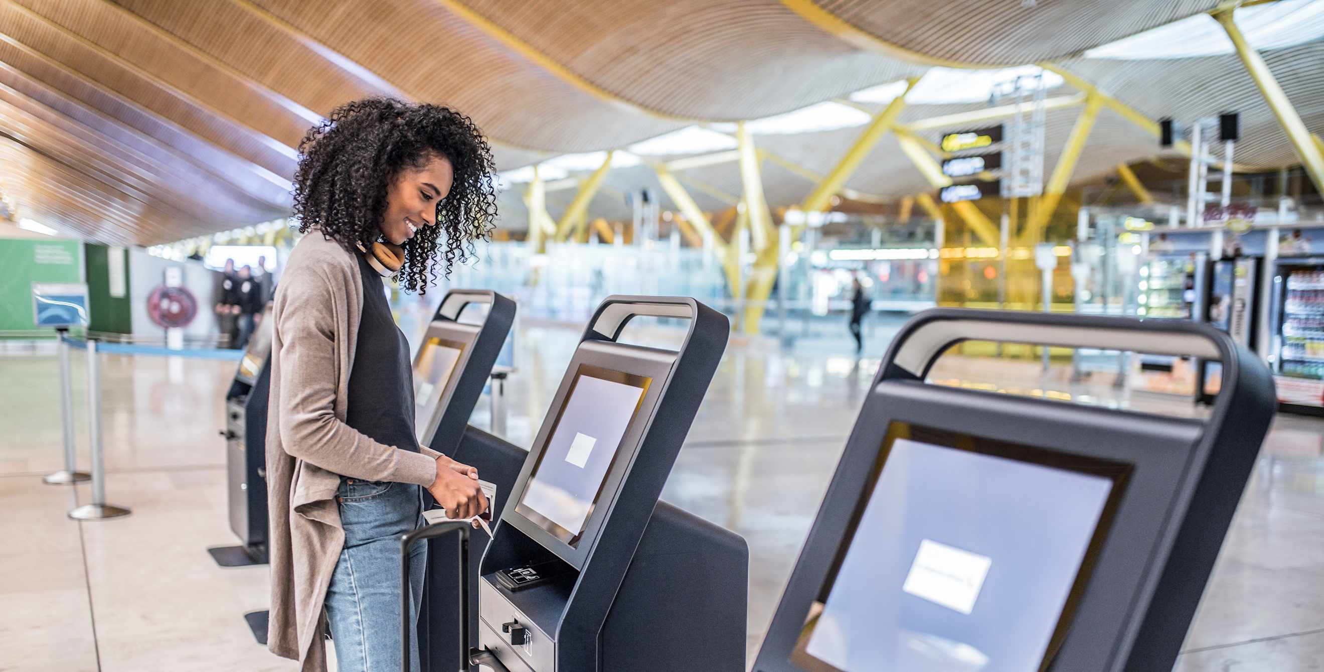 A woman uses a kiosk to check in at the airport before her flight.