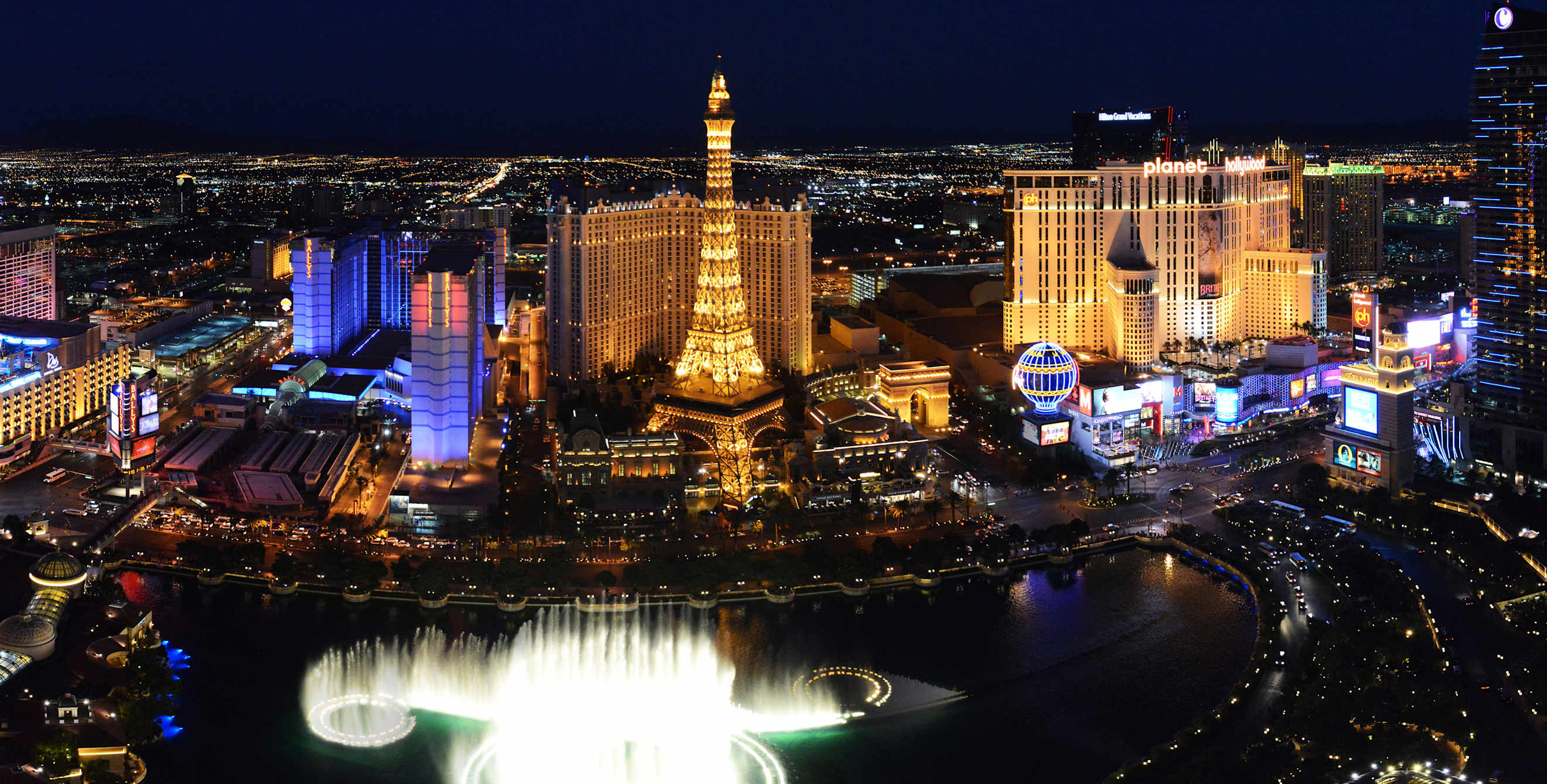 The Las Vegas Strip lit up at night with the Belagio Fountains erupting.