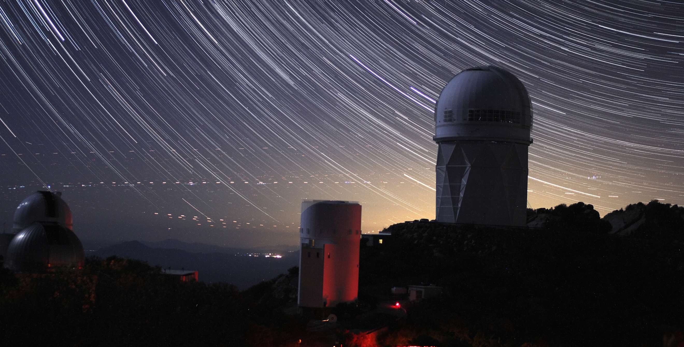 a timelapse image of a night sky with stars at an observatory