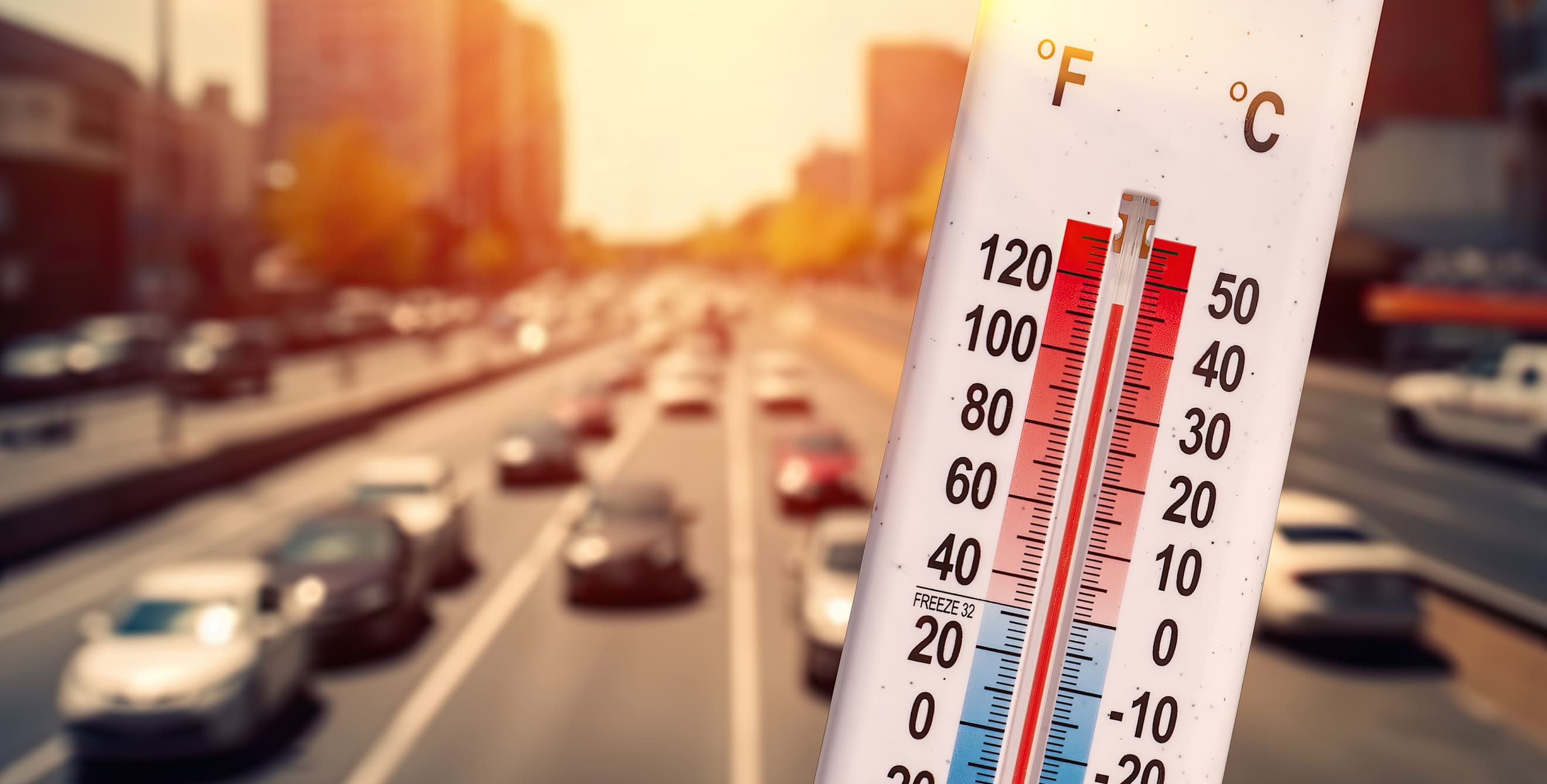 a thermometer shows a high temperature in front of a highway full of cars