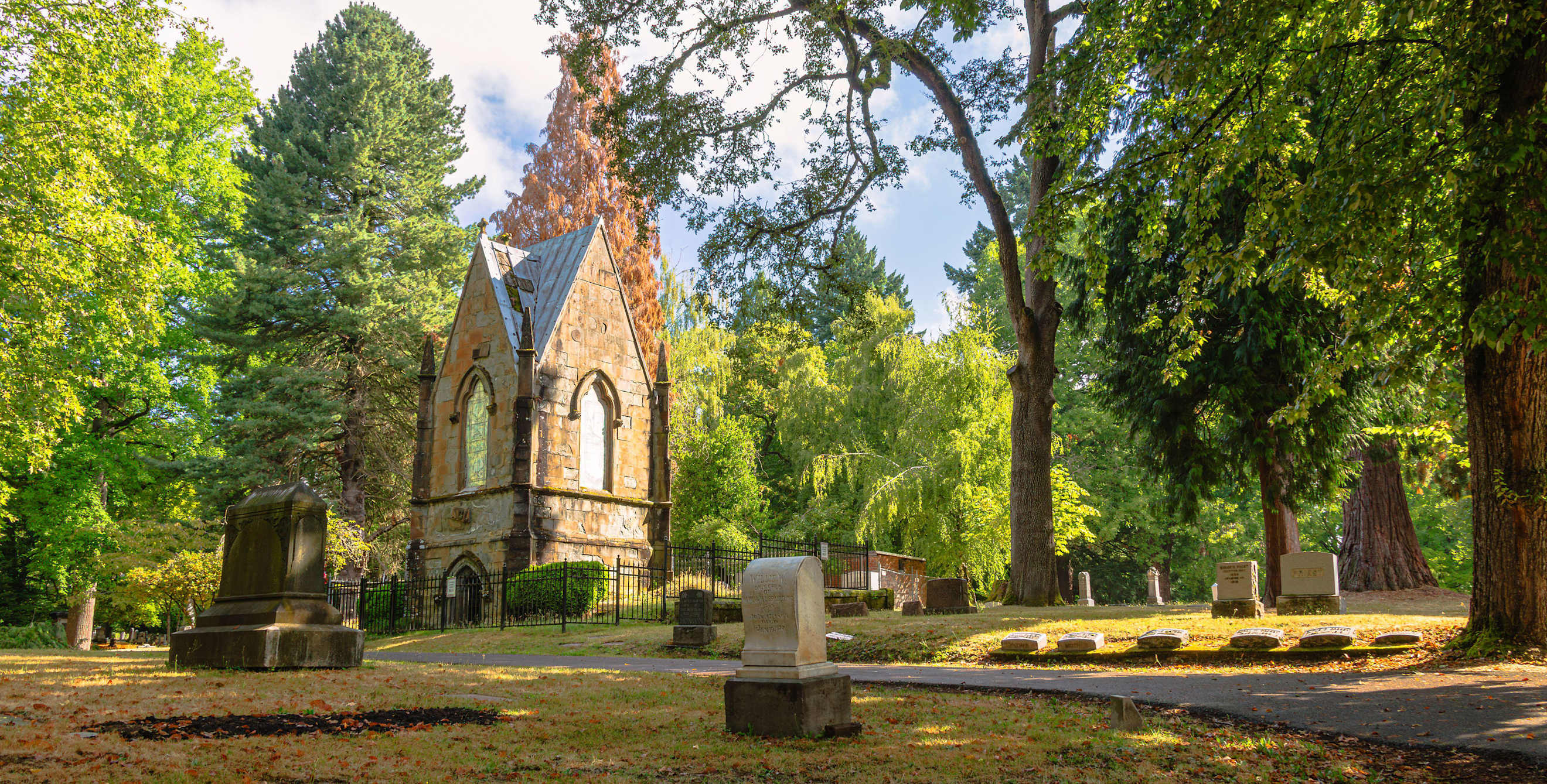 A stone mausoleum in a woodsy cemetery.