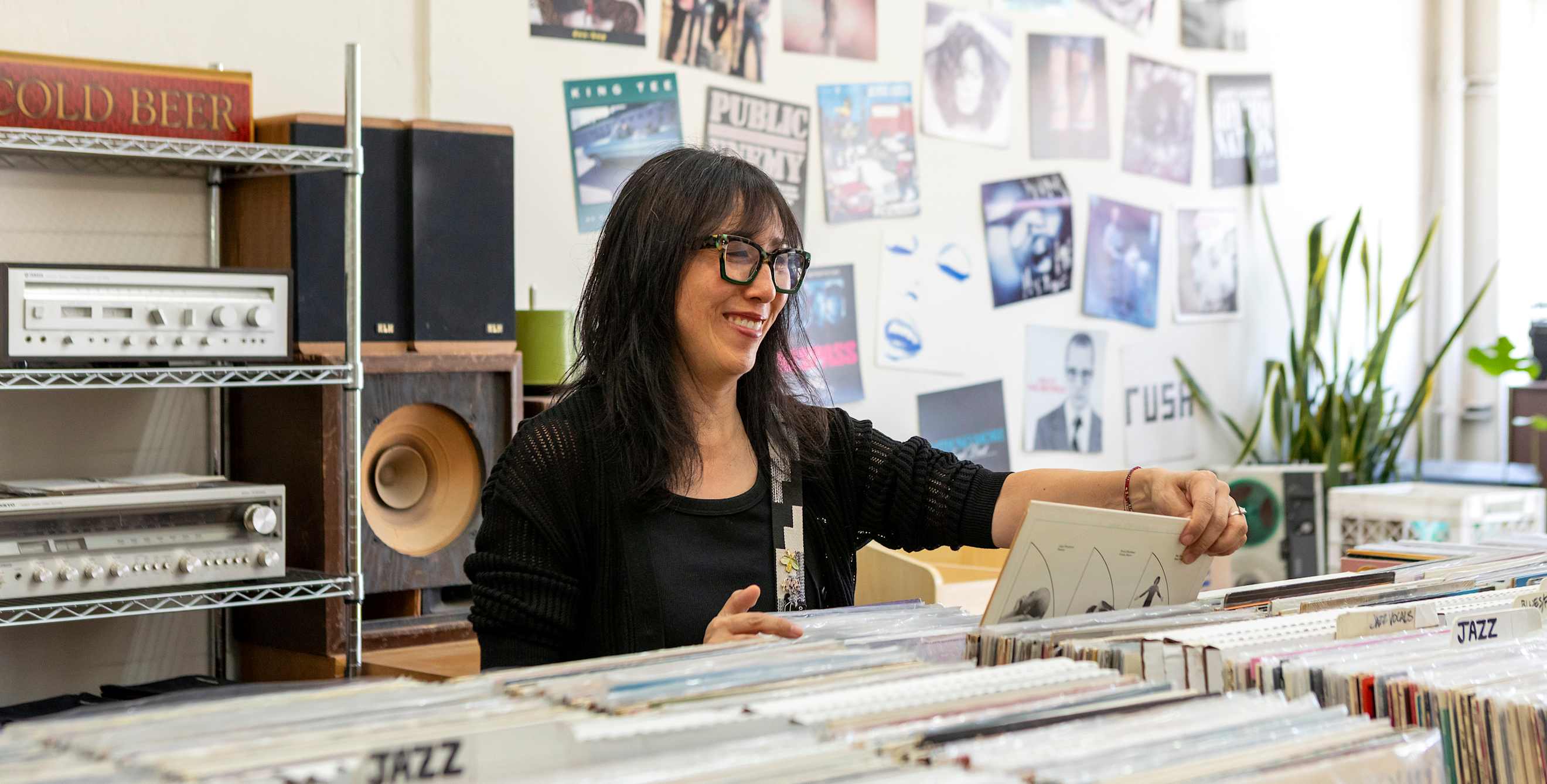a woman with black hair looks through vinyl at a record store