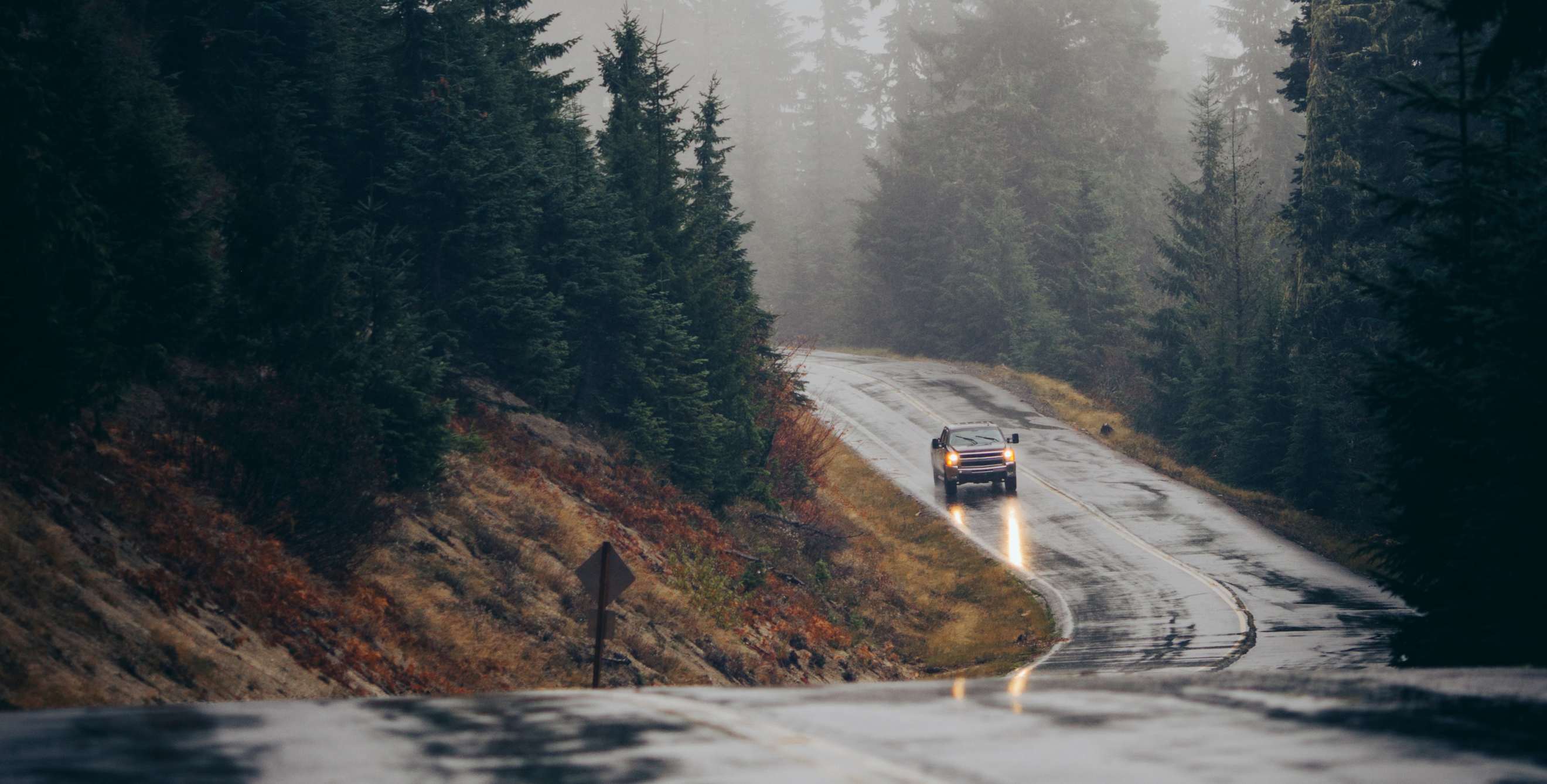 A truck drives on a wet road in the rain.