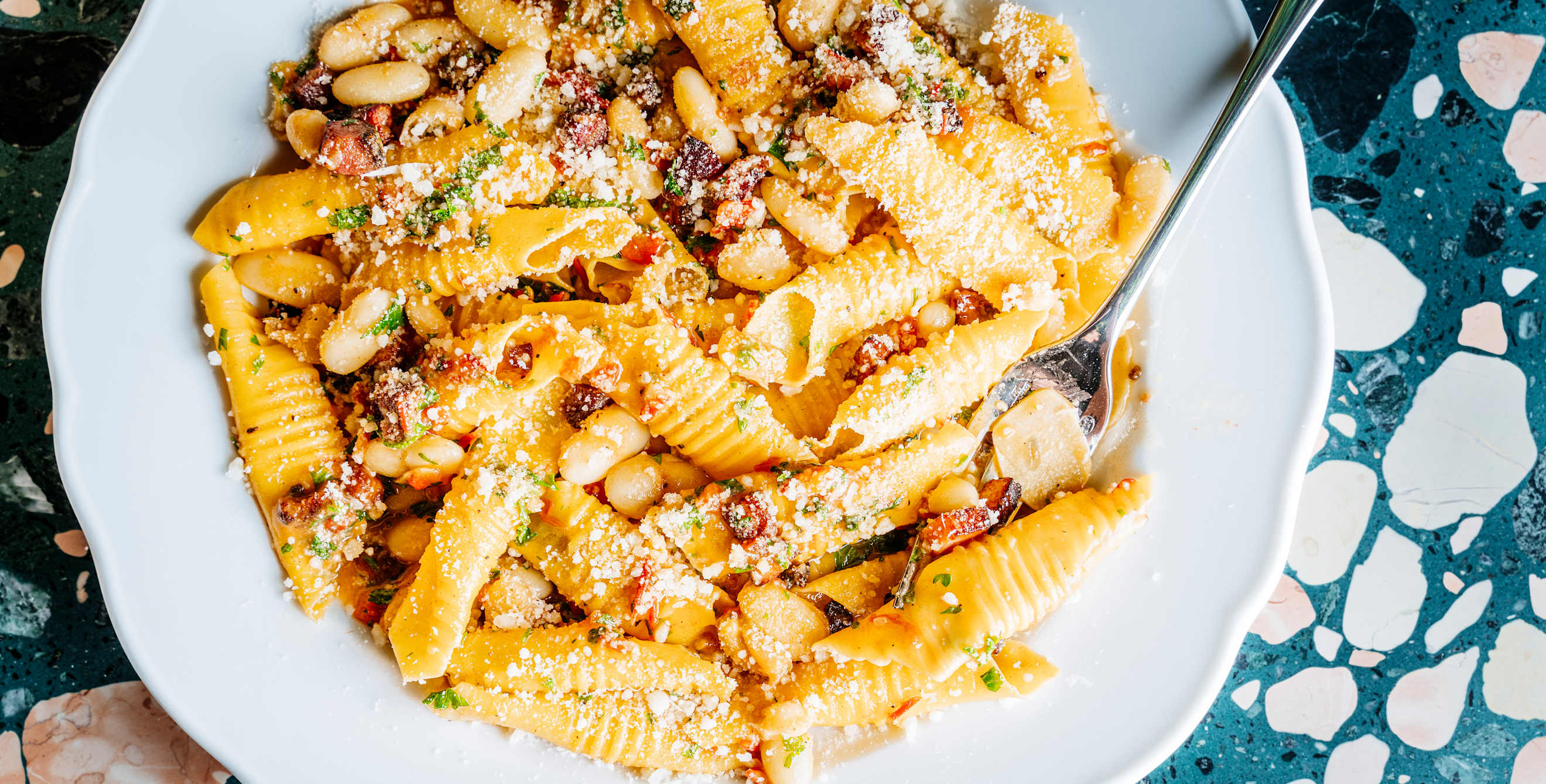 a close-up on a plate of fresh pasta with white beans and herbs