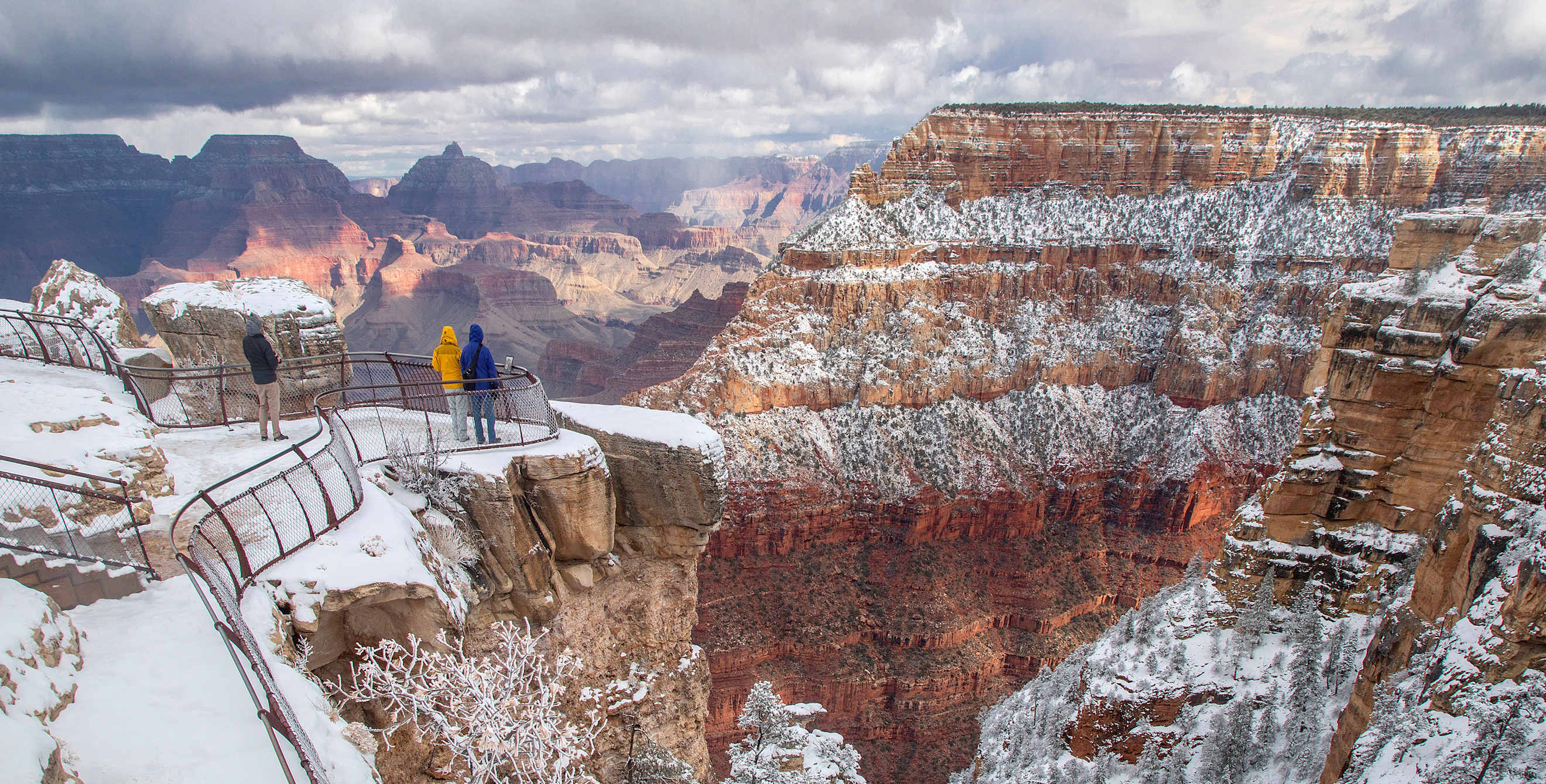 People stand at an overlook on the Rim Trail in Grand Canyon National Park, Arizona, to see the canyon dusted in snow.