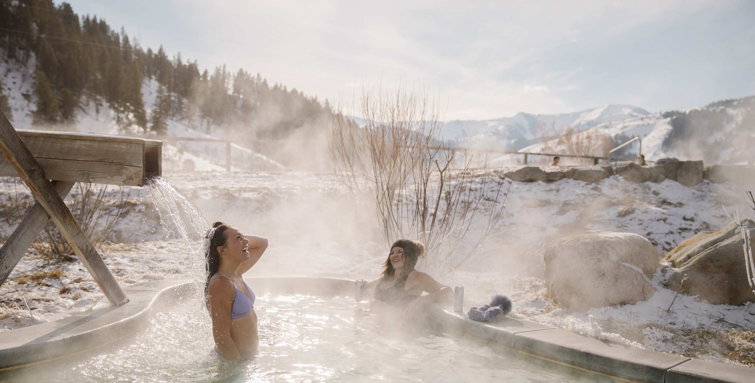Friends soak at Astoria Hot Springs Park in Wyoming on a winter day.