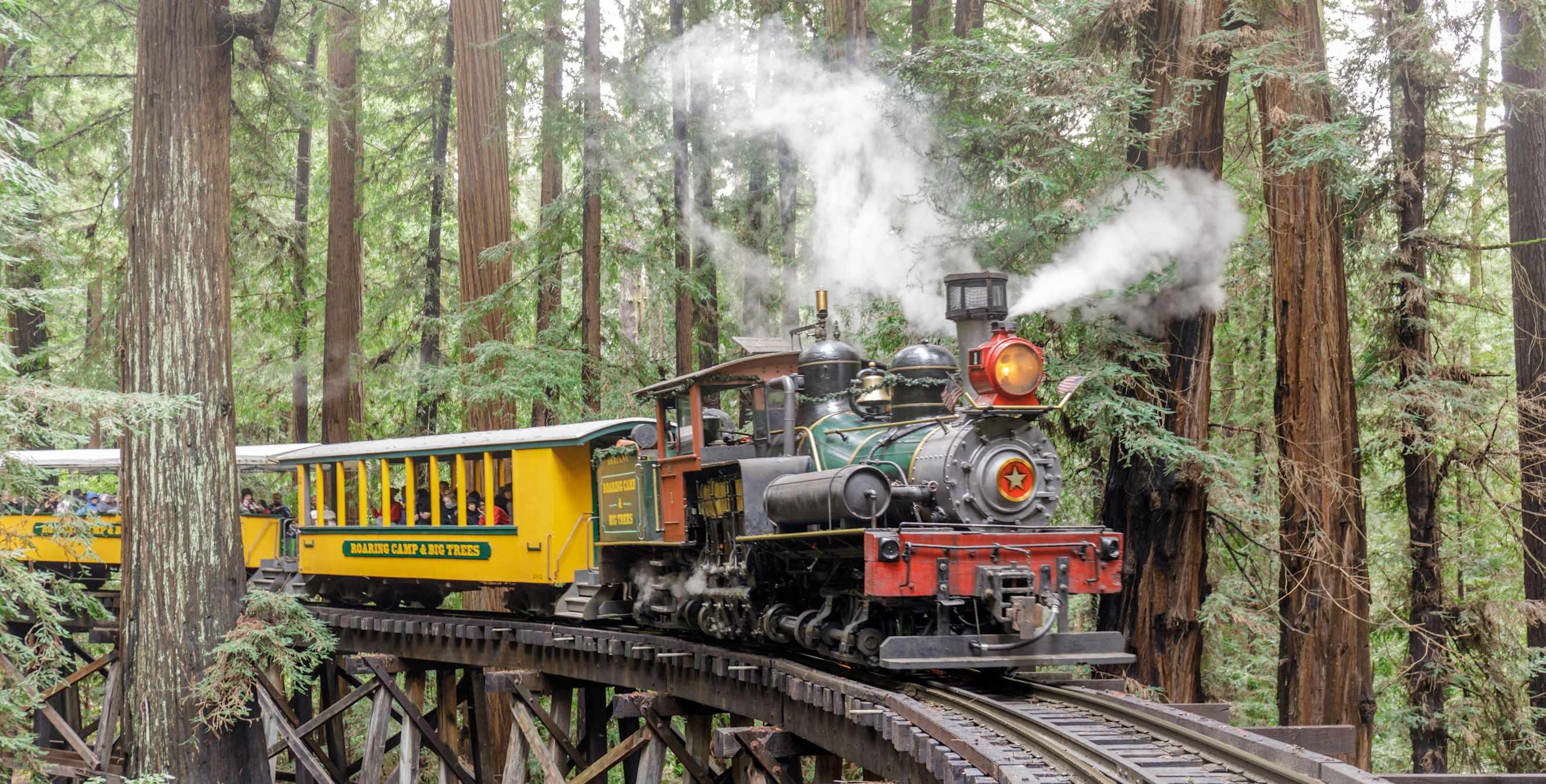 A steam train goes through redwood trees at Roaring Camp in Felton, California