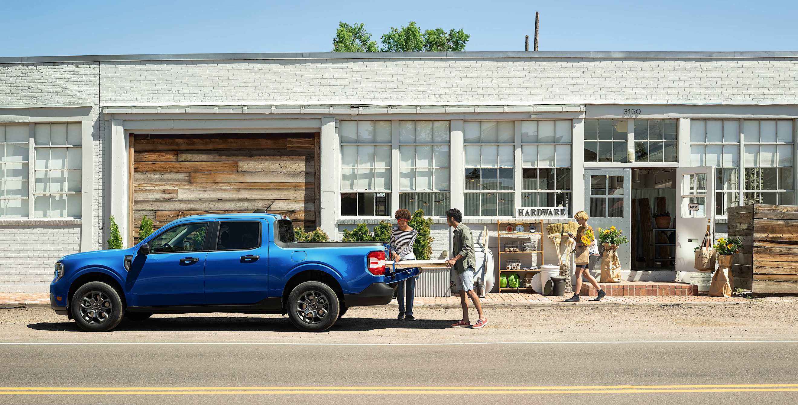 A couple load wood into the back of a 2025 Ford Maverick XLT.