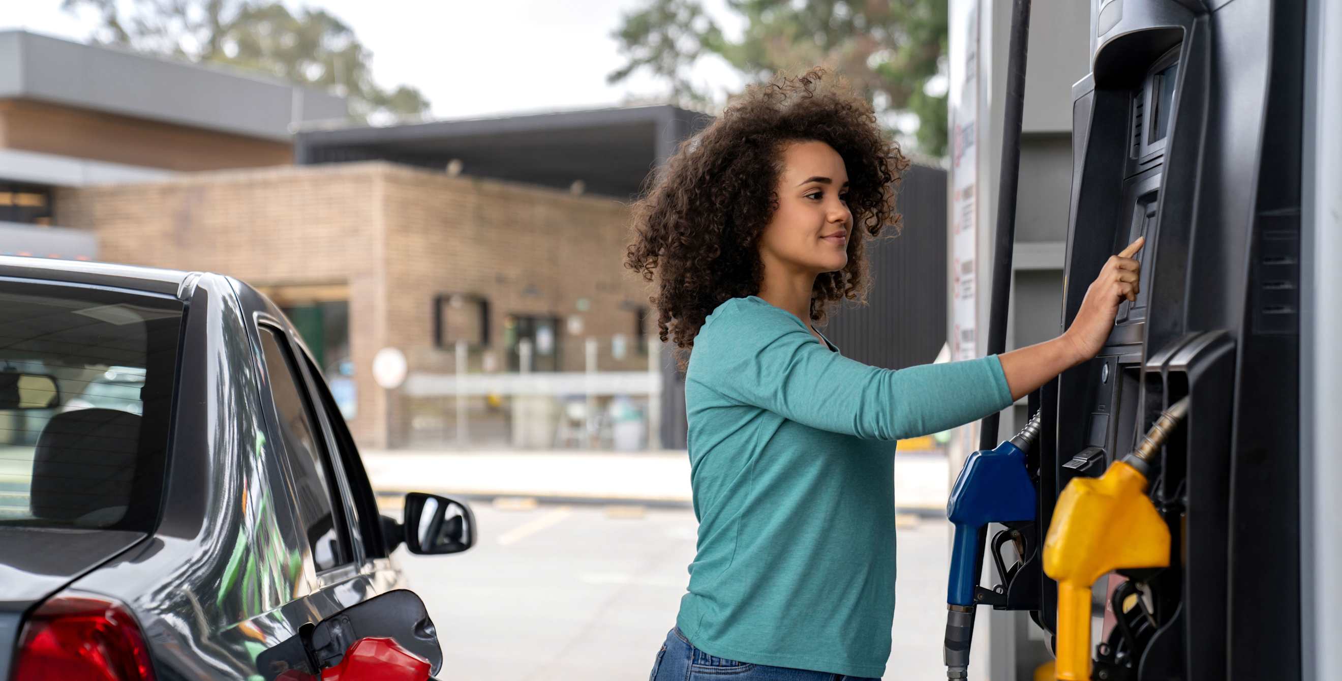 A woman selects her preferred gas at a gas station.