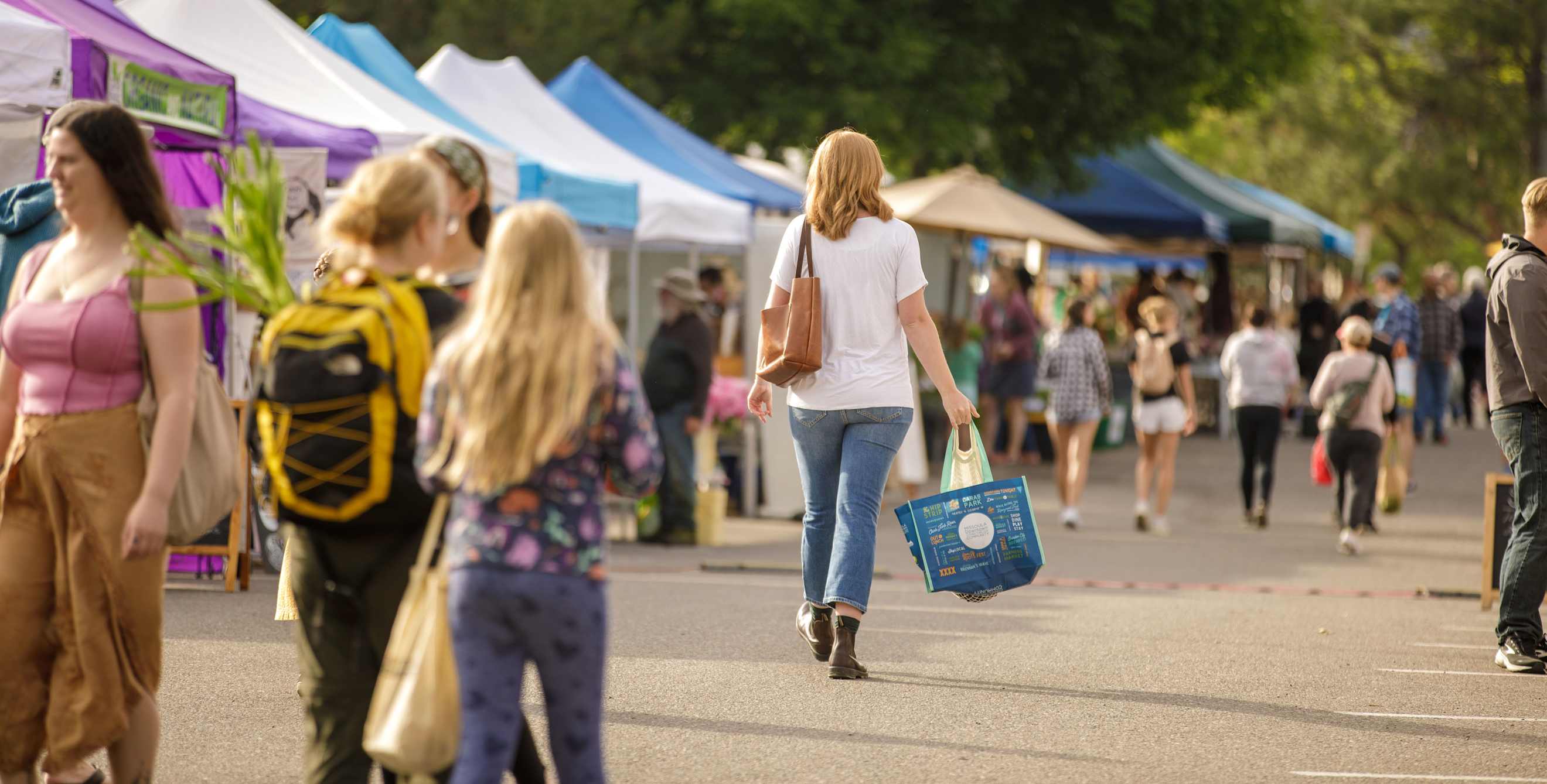 Shoppers walk between booths at the Clark Fork River Market in Missoula, Montana.