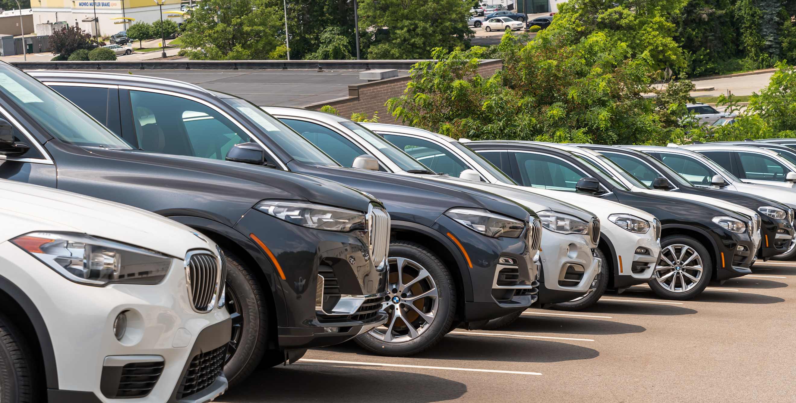 A row of parked cars in a car dealership lot.