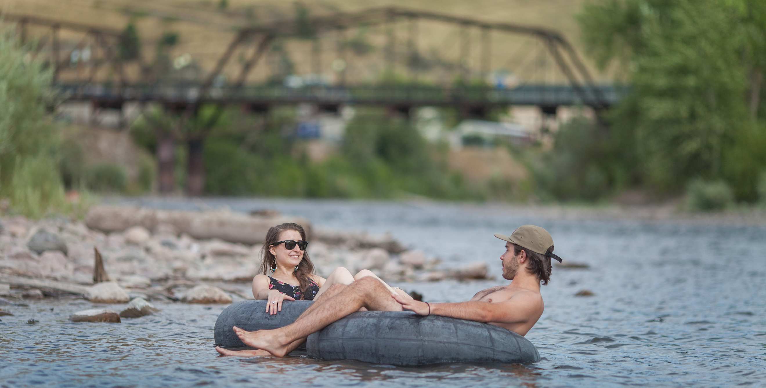 a woman and a man float in inner tubes on the Clark River in Missoula, Montana