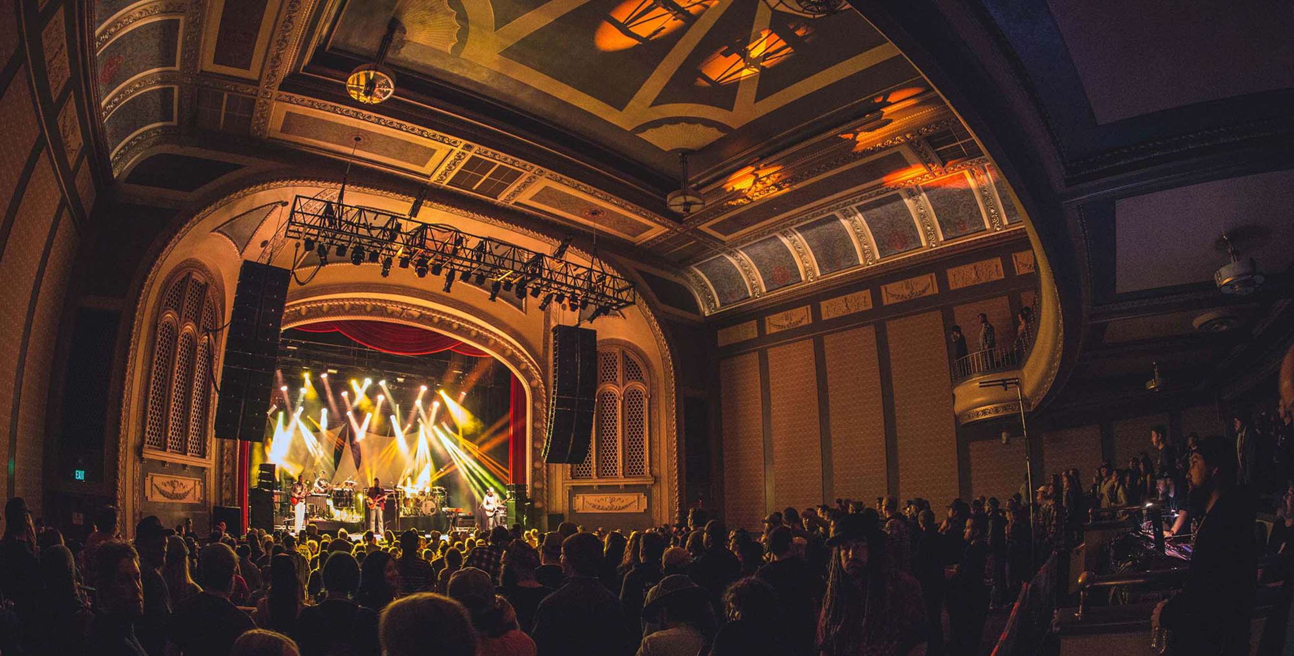 a concert hall packed with people with a band on stage