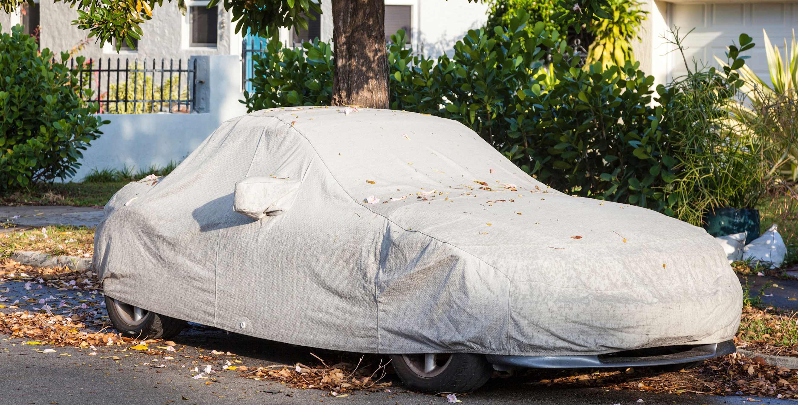 A car parked on the street under a car cover.