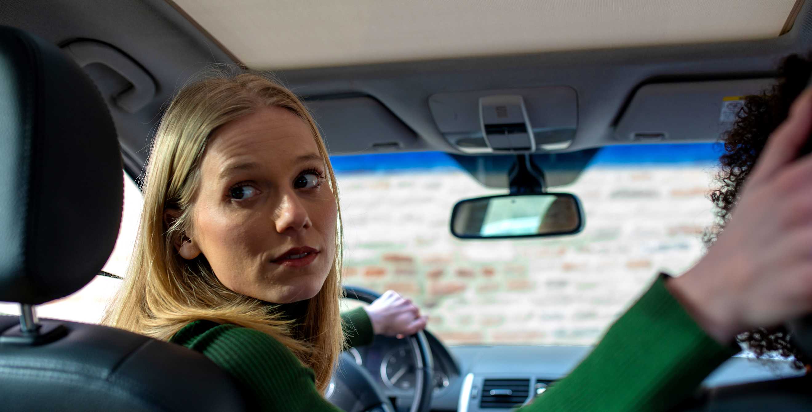 A driver looks over her shoulder while backing up her car.