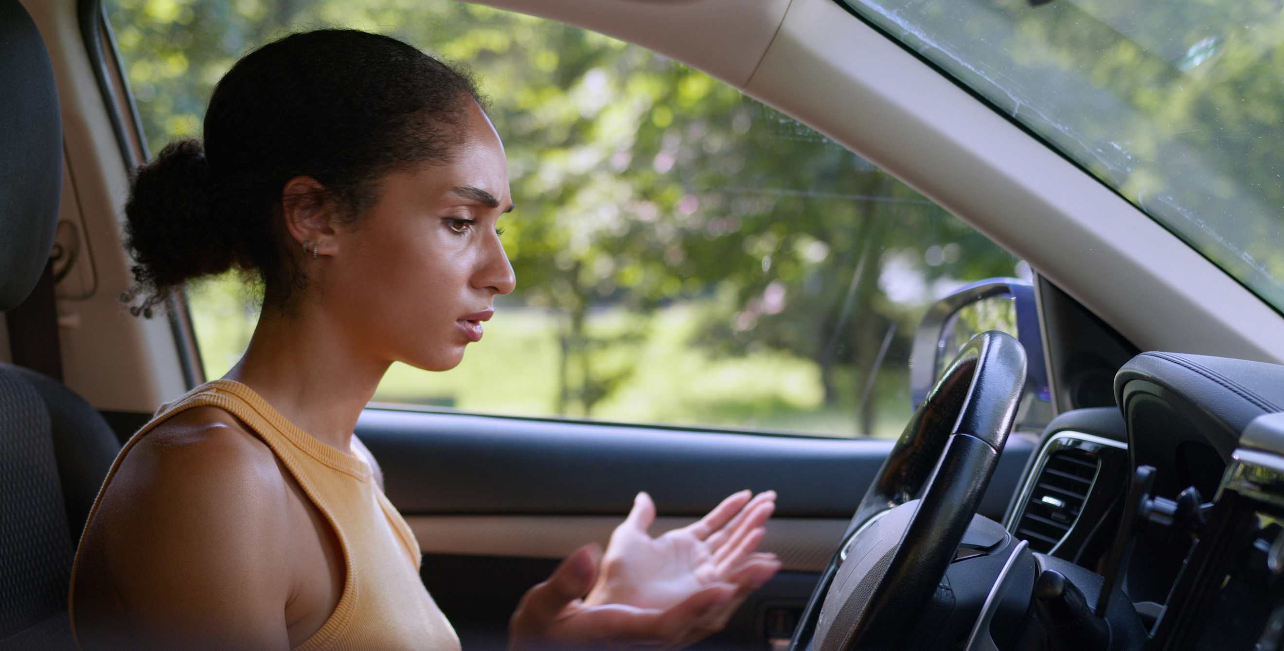 A woman sits in her car trying to figure out why it won't start.