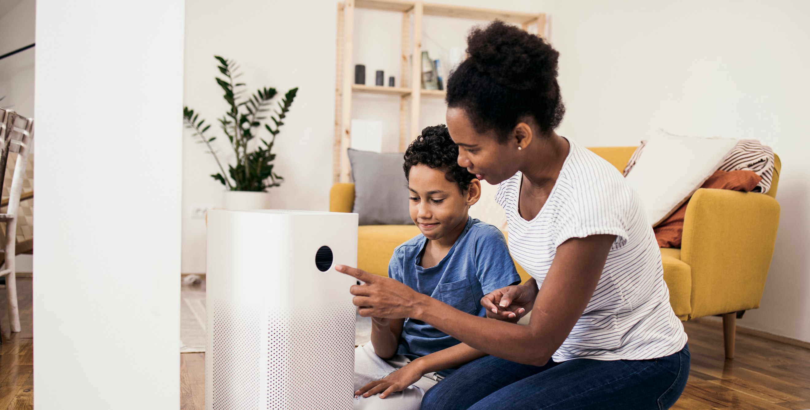 A mother and son turn on their air purifier in their living room.