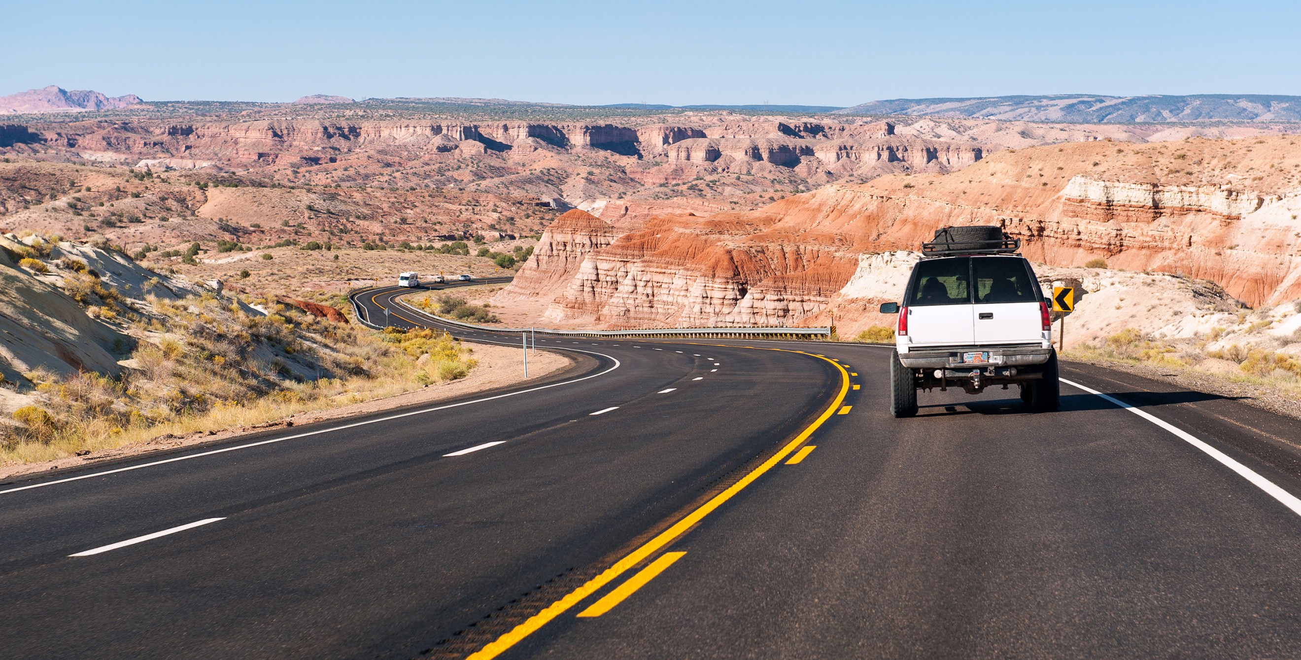 A full-sized SUV drives through the Arizona desert on a clear day.