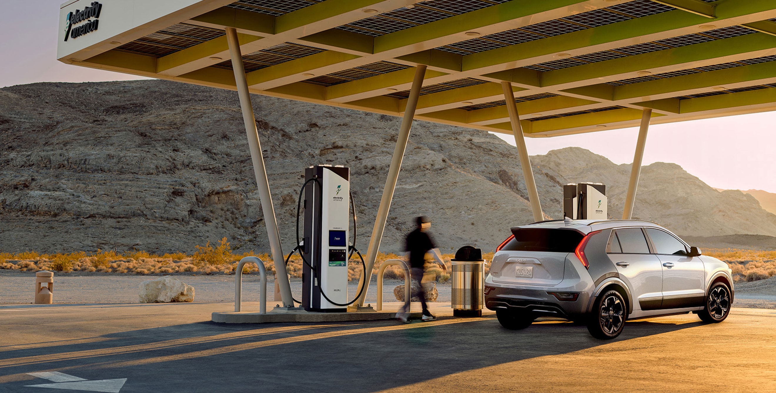 A driver charges his electric Kia at an Electrify America charging station.