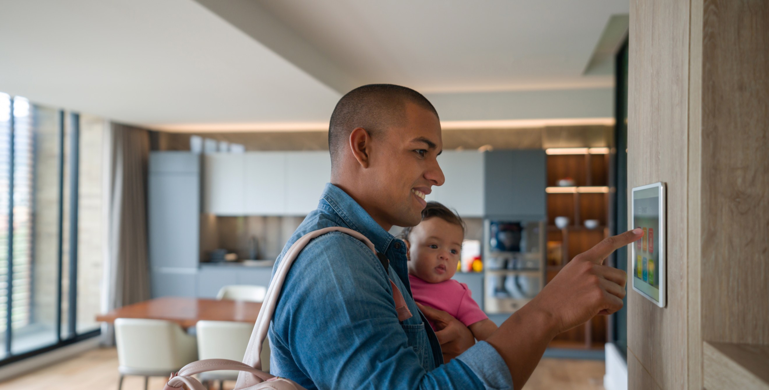 A dad turns on his home security system as he leaves the house with his baby.