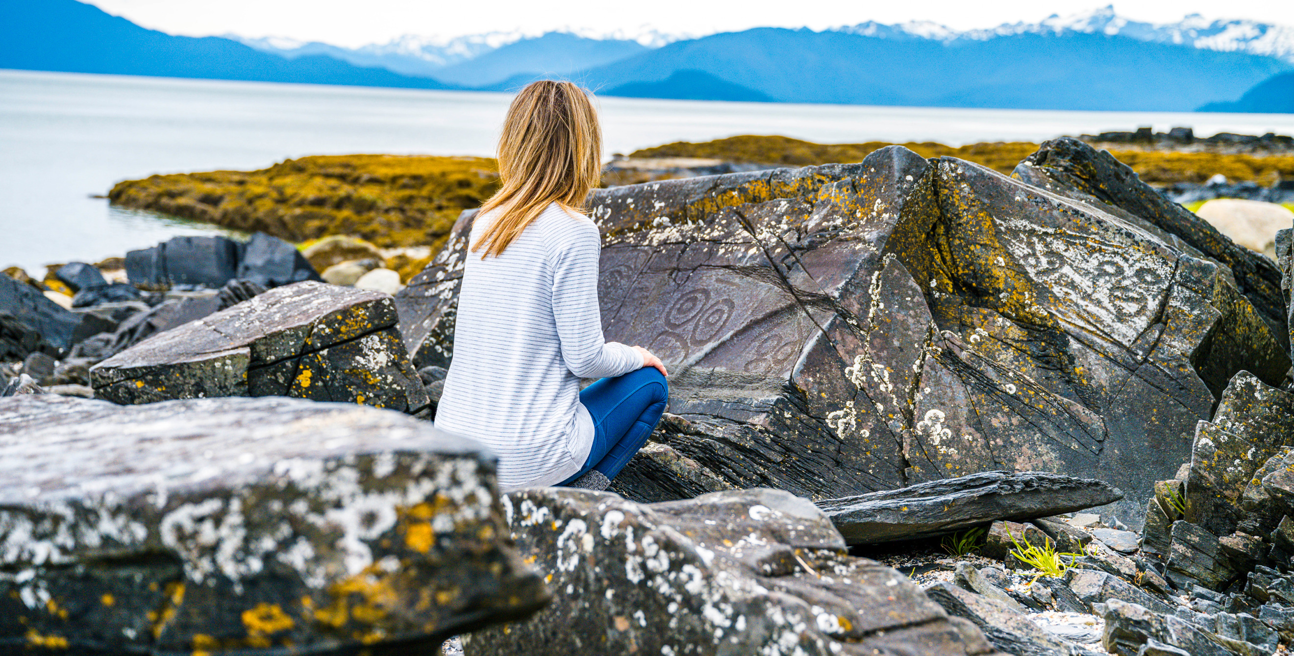 A woman looks at a rock at Petroglyph Beach State Historic Site in Wrangell, Alaska.