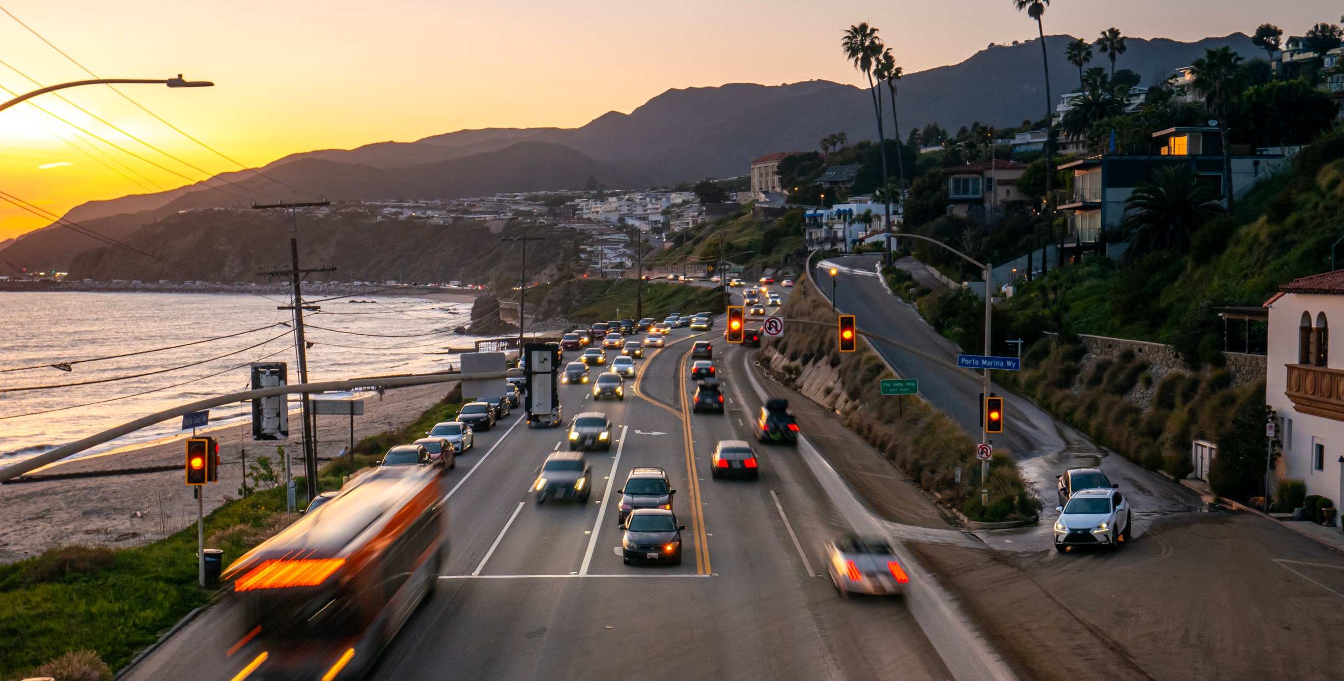 Cars drive along Highway 1 in California at sunset.