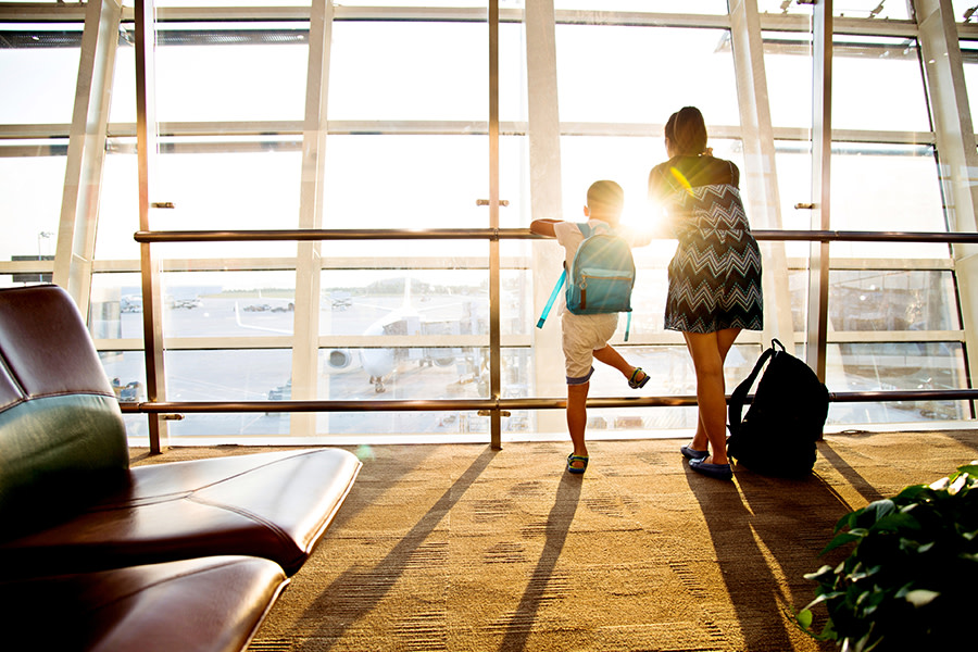 picture of a mother and son looking out the window at the airport during sunset