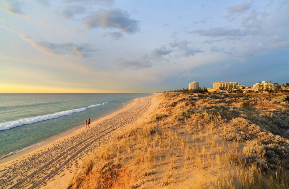 A couple strolls along Perth’s Scarborough Beach at sunset, image