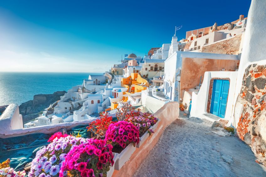 Oia village in Santorini Greece blue sky with purple flowers, picture