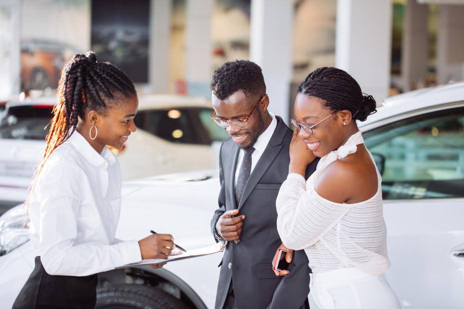 African American couple talk to a car sales person in the dealership, image