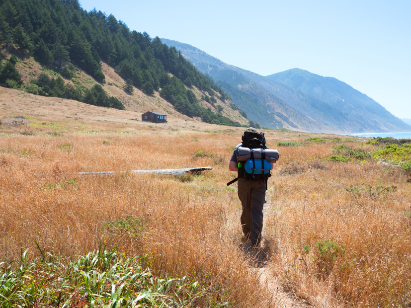 picture of a hiker walking on a trail along the Lost Coast with ocean and mountains in the background