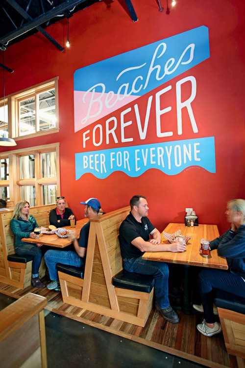 Public Coast Brewing Co. interior with patron seated in all wood booths, picture