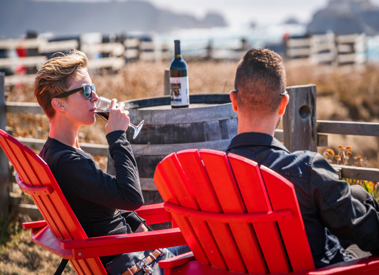 couple seated in adirondack chairs sip wine at Pacific Star Winery in Mendocino, California, picture