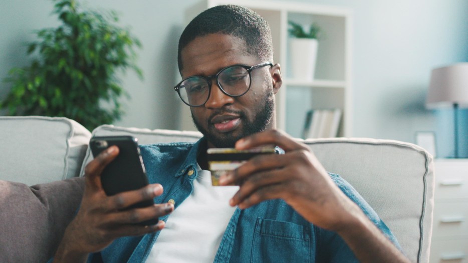 African American man shops on phone with credit card, picture