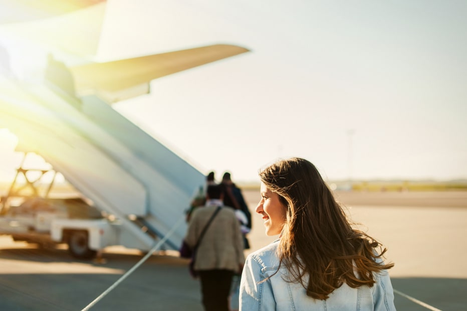 Woman boards an airplane on the tarmac on a sunny morning, picture