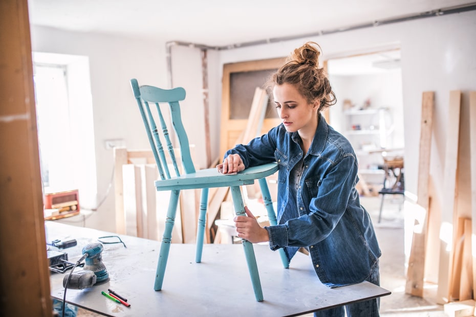 A woman repairs a chair in her under-construction home, image