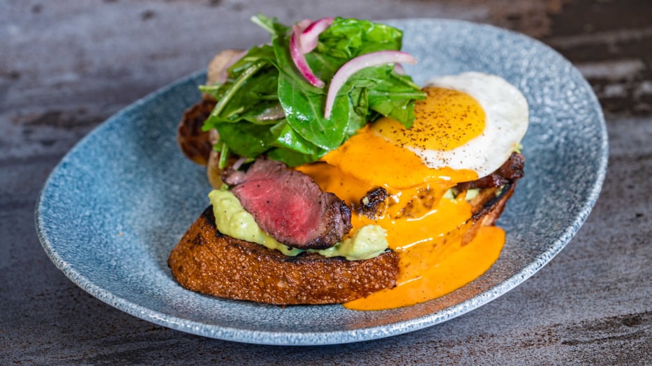 New York avocado toast topped with New York steak, an egg, piquillo-butter sauce, and confit potatoes at the Lamplight Lounge on Pixar Pier in Disneyland California Adventure