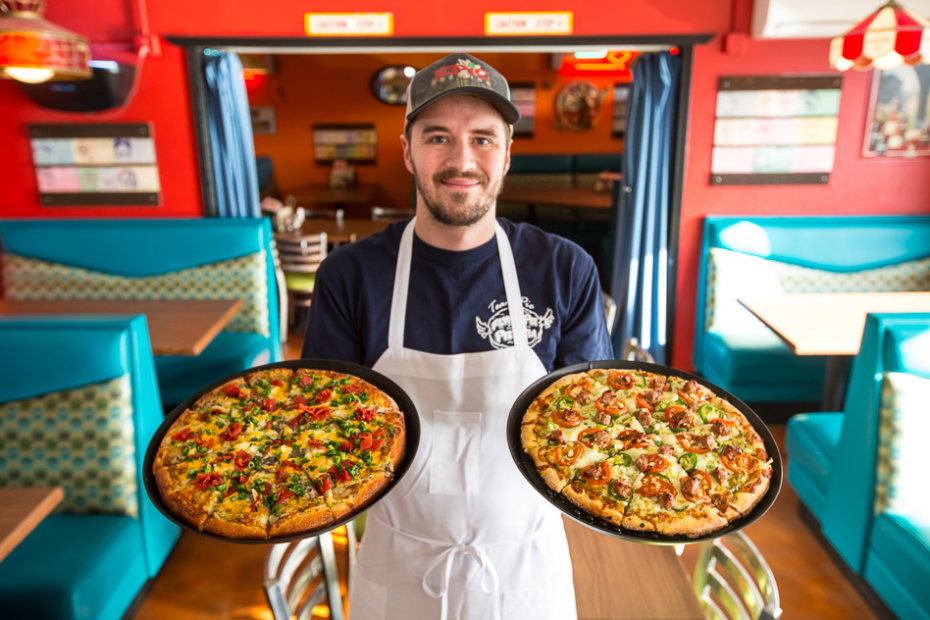 picture of a server with two pizzas at Flying Pie Pizzaria in Boise, Idaho