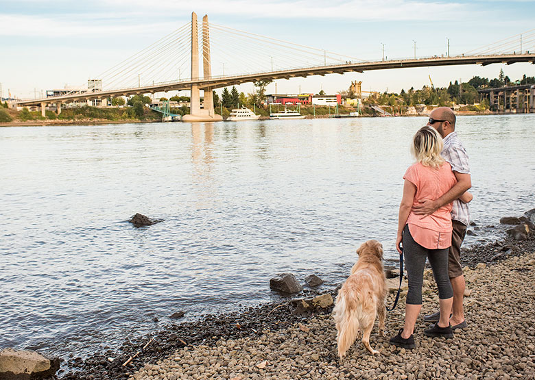 couple with dog along the Willamette River shoreline savor the view of Portland at Poet's Beach in Oregon, picture