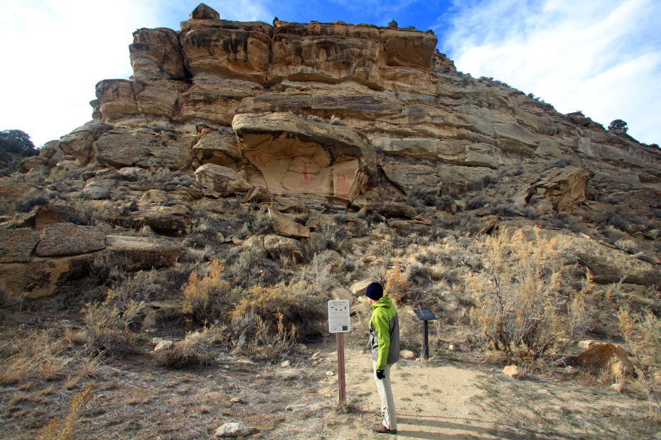 man reading sign in front of ancient petroglyphs and rocky structures at Canyon Pintado Historic District, photo