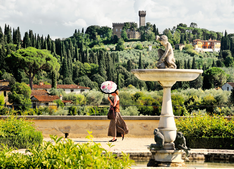 woman with parasol strolls past fountain at Boboli Gardens in Florence, Italy, picture