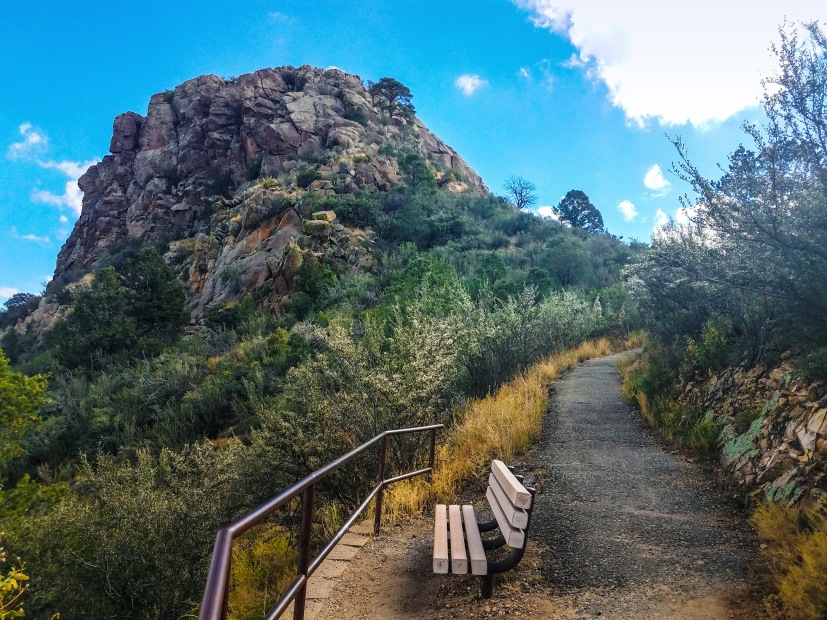 Photo of a bench next to a hiking trail on a mountain