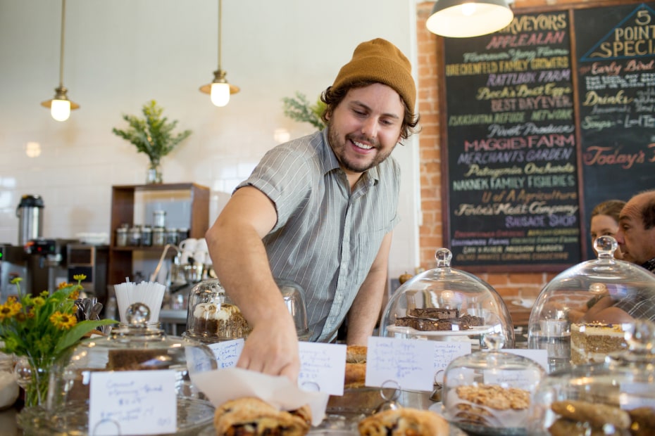 young man reaches in the baked goods at 5 Points Market & Restaurant in Tucson, Arizona, picture