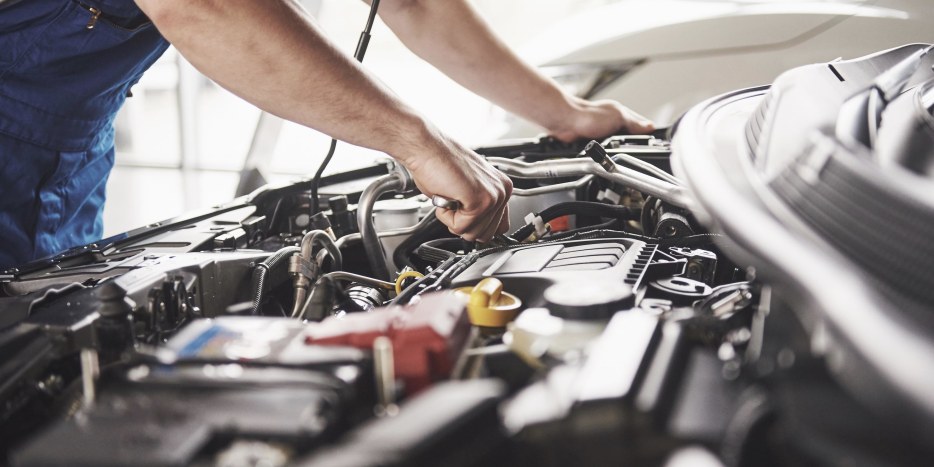 a mechanic works on an open car engine, picture