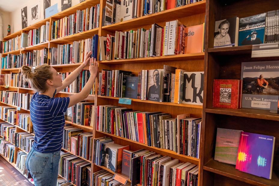 woman reaches up for shelved book at City Lights bookstore in San Francisco, California, picture