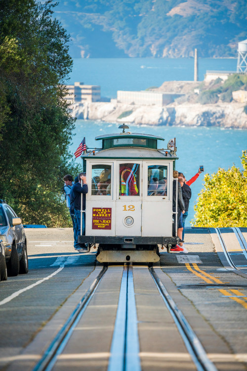 cable car full of riders with Alcatraz in distance in San Francisco, California, picture