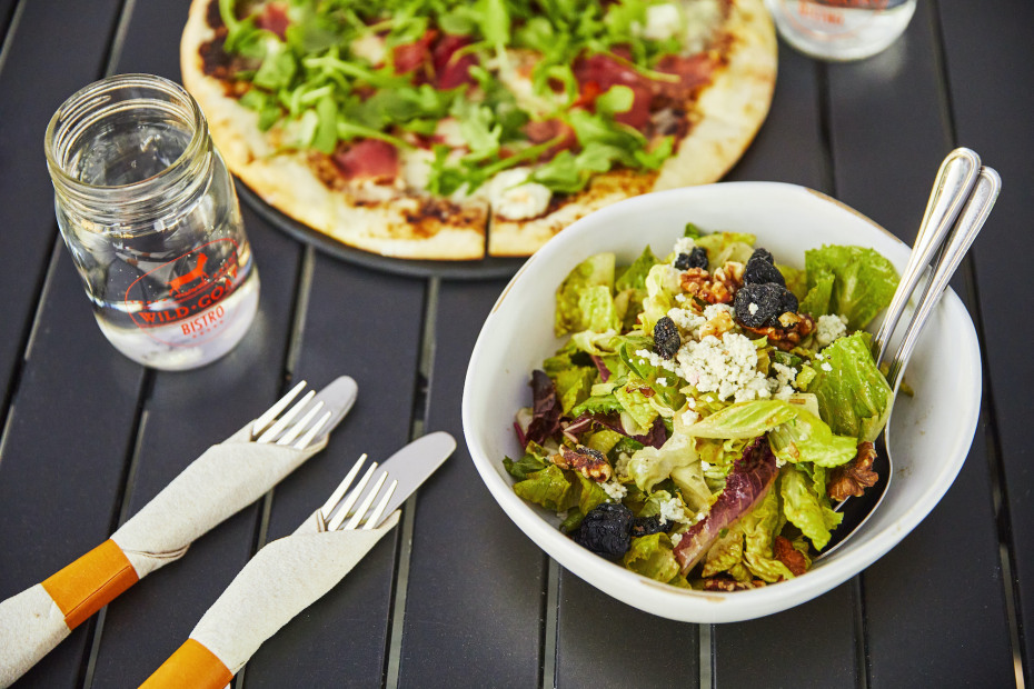 The Cherry Blue Salad and Four Cheese Fig & Pig Pizza sitting on table with silverware at Wild Goat Bistro.