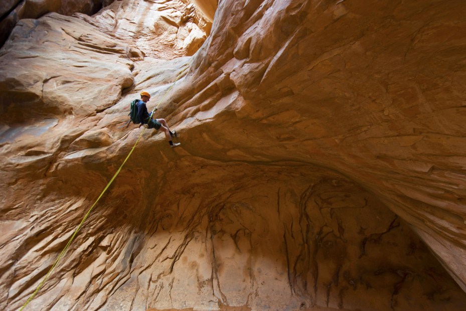 A man descends into a canyon at Arches National Park, image